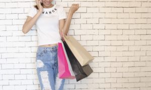 girl holding shopping bags against wall